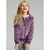 A young girl with long blonde hair smiling and looking upward, wearing a purple zip-up hooded jacket with a plush velvety texture, paired with gray pants, against a solid light gray studio background.