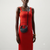 A model wearing a bright red sleeveless midi dress and a black crescent-shaped shoulder bag with a circular top handle, posed against a light gray studio background.
