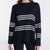 A woman wearing a navy blue knit sweater with horizontal white stripes across the chest and sleeves, shown against a plain light background.