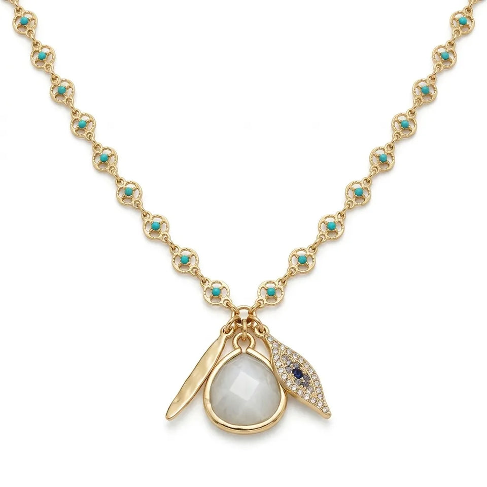 A gold necklace featuring a repeating floral link pattern with small turquoise stones, a teardrop-shaped milky white stone pendant, and two leaf-like charms, one gold and one adorned with tiny clear stones and a small blue stone, on a white background.