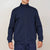 A man wearing a navy blue full-zip fleece jacket with a mock neck collar, paired with matching navy pants, against a plain light beige background.