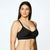 A woman modeling a black wireless bra against a plain white studio background.
