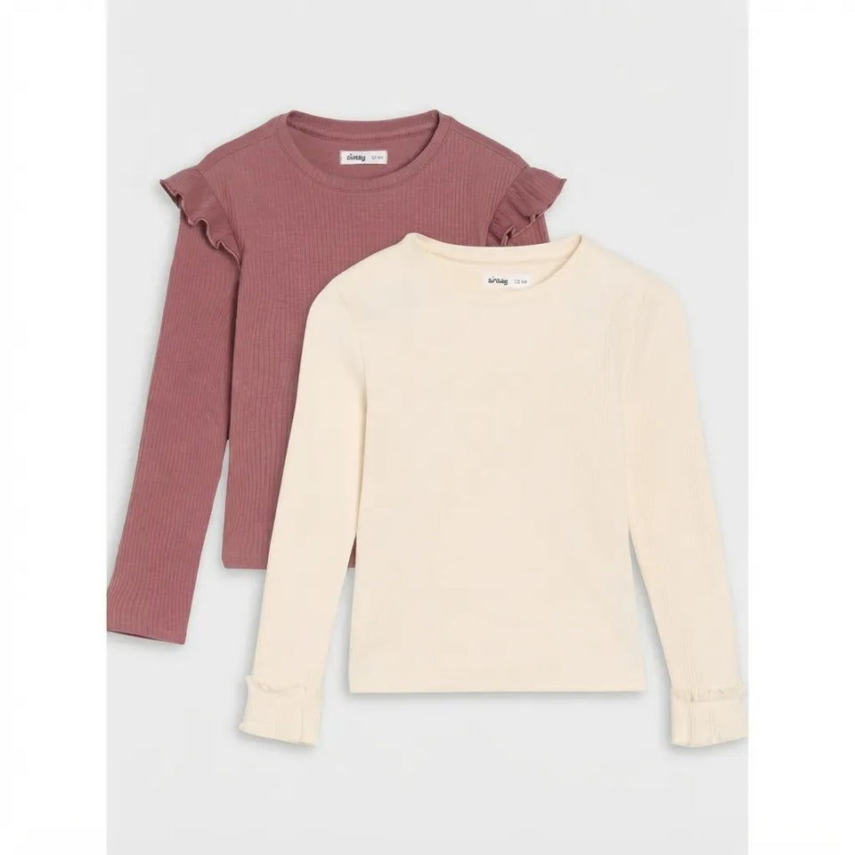 Two long-sleeve ribbed knit tops for girls, one in dusty rose with ruffle details on the shoulders and sleeves, and one in cream with matching ruffle details, displayed on a light gray background.