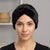 A woman wearing a black plush, textured headband with a knotted twist design, shown from the chest up against a soft gray background.