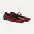 A pair of glossy patent leather Mary Jane flats in deep burgundy red, featuring a single strap with a small silver buckle and a low block heel, shown on a light off-white background.