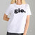 A woman wearing a white short-sleeve crewneck t-shirt with the word 'gio.' printed in black across the chest, paired with black pants, against a solid gray background.