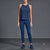 A woman modeling a matching athletic set consisting of a sleeveless navy blue top and high-waisted navy blue leggings, paired with navy blue sneakers, against a dark gray studio background.