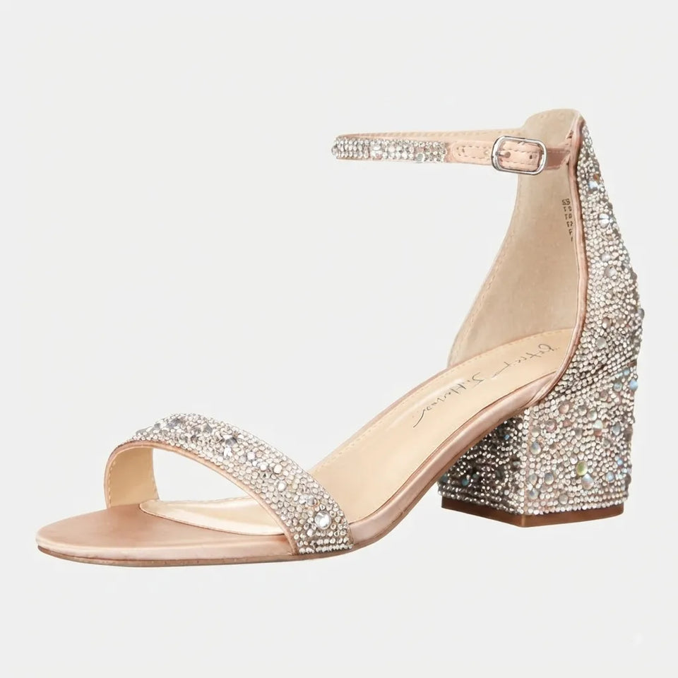 A single women's heeled sandal with a block heel, ankle strap, and open toe, covered in sparkling rhinestones. The upper and heel are a champagne rose gold tone, while the insole is a light nude beige.