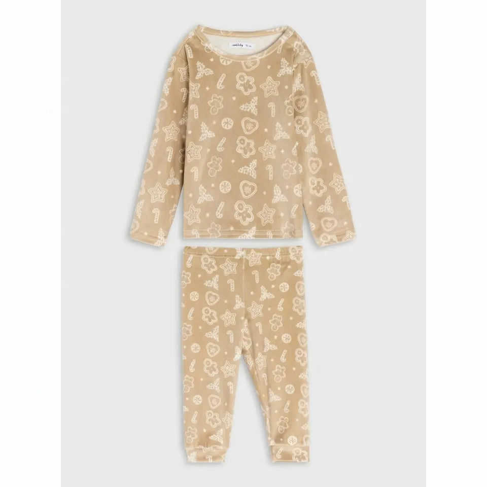 A two-piece children's pajama set in a warm beige color, featuring a long-sleeve top and matching pants with an all-over cream-colored whimsical pattern of stars, hearts, and candy canes, displayed flat against a light gray background.