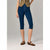 A model wearing dark blue cropped capri jeans, paired with a tan top and leopard-print flat shoes, standing against a light gray studio background.