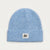 A light blue ribbed knit beanie hat with a folded cuff and a small white rectangular patch on the front that reads 'TRISTY VIBES'.