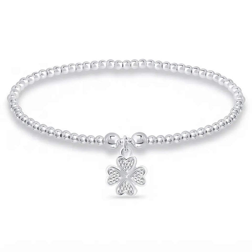 A silver beaded stretch bracelet with a dangling four-petal flower charm, shown on a clean white background.