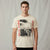 A man wearing a cream-colored graphic t-shirt with a black and white cityscape print and red vertical 'NEW YORK' text, set against a neutral gray backdrop.