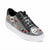 A low-top platform sneaker featuring a black and white houndstooth pattern, black leather trim, white laces, and various decorative charms including a skull, a cat face, and red hearts.