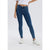 A model wearing a pair of high-waisted, skinny blue jeans with a white crop top and white sneakers, shown from the waist down against a light gray studio background.