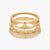 A stack of three gold rings with unique designs, including a scalloped band, a beaded textured band, and a smooth thin band, displayed on a light gray background.