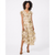 A woman modeling a champagne beige and gold floral midi dress with ruffled cap sleeves and a tie waist, paired with brown strappy heels, against a plain white studio background.