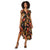 A woman modeling a short-sleeve midi dress with a black base and a vibrant floral print in orange, pink, and yellow, paired with black strappy high-heeled sandals against a plain white background.