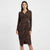 A woman modeling a long-sleeve wrap-style midi dress with a brown and black zebra-like animal print pattern, set against a plain light gray studio background.