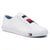 A white low-top canvas sneaker by Tommy Hilfiger, featuring the signature red, white, and navy blue flag stripe across the side, a matching flag logo on the white rubber midsole, and a blue lining visible inside the collar.