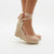 A pair of women's espadrille wedge sandals in a light nude pink color, shown on a model's feet against a clean white background.