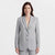 A woman modeling a light gray pinstripe blazer with matching trousers against a clean white studio background.
