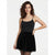 A woman modeling a black sleeveless mini dress with thin spaghetti straps, a scoop neckline, and a flared tulle skirt with a lace hem, set against a plain light gray studio background.