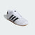 White Adidas sneaker with black stripes on a light gray background