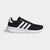 Black Adidas sneaker with white stripes on a light gray background