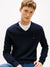 Man wearing a navy blue sweater with a small logo on a light gray background