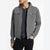 A man wearing a gray hooded zip-up jacket over a dark gray henley shirt and black pants, photographed against a clean white studio background.