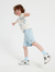 A boy wearing a blue short-sleeved shirt and blue shorts, standing against a white background.