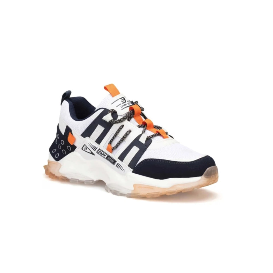 A white and navy blue chunky sneaker with bright orange accents, featuring a thick translucent sole and decorative chain laces, shown against a plain white background.