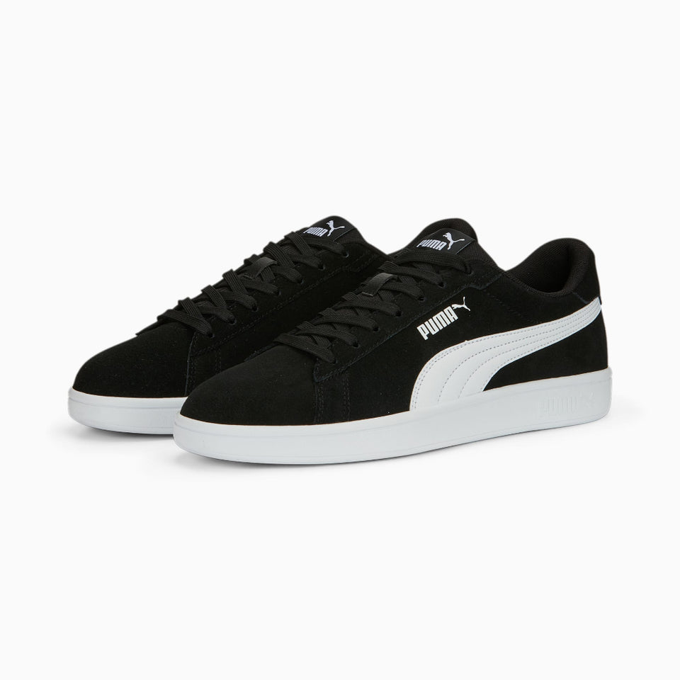 Pair of black and white Puma sneakers on a light gray background