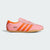 Pink Adidas sneaker with orange stripes on a light gray background
