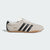 Beige Adidas sneaker with black stripes on a white background