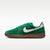 Green sneaker with a white swoosh logo on a white background