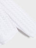Close-up of a textured white sweater on a light gray background