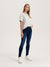 Woman wearing a white top and dark blue jeans on a light gray background