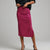 A model wearing a bright magenta pink sequined midi skirt with a side slit, paired with a black top and black heels, against a neutral gray studio background.