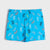 Bright blue shorts with an all-over pattern of cartoon game controllers in black, white, yellow, and orange, displayed flat against a light gray background.