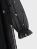 Black sheer fabric with gold star patterns on a white background