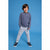 A young boy modeling a long-sleeve striped henley shirt in navy and light gray, paired with light gray jogger pants and navy sneakers, standing against a solid blue studio background.