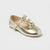 A single metallic gold flat shoe for a child, featuring a Mary Jane strap design with two decorative bows on the top, photographed on a light gray background.