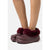 A person wearing burgundy faux-fur clogs with a matching burgundy sole, shown from the calves down against a light gray background.