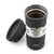 A matte black insulated travel tumbler with a matching lid leaning beside it, shown on a clean white background. The tumbler is open, revealing coffee inside, and has a white wrap label reading 'ello NO MORE lukewarm COFFEE' with a small green logo.