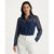 A woman modeling a navy blue sheer long-sleeve button-up shirt with two chest pockets, paired with white trousers, against a plain white studio background.