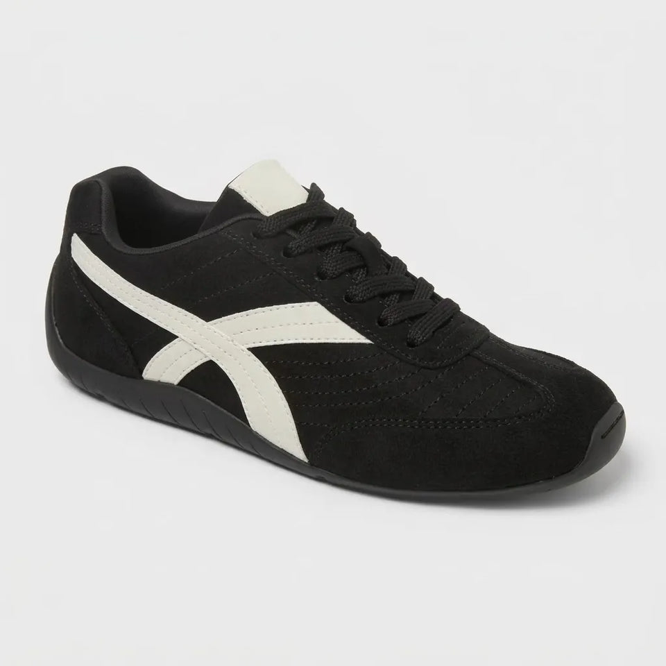 Black sneaker with a white stripe on a light gray background
