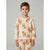 A young boy wearing a cream-colored ribbed long-sleeve pajama top and matching pants, both featuring an all-over print of brown and orange foxes, standing against a neutral gray background.