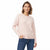 A woman modeling a light pink crewneck knit sweater with blue jeans against a plain white background.